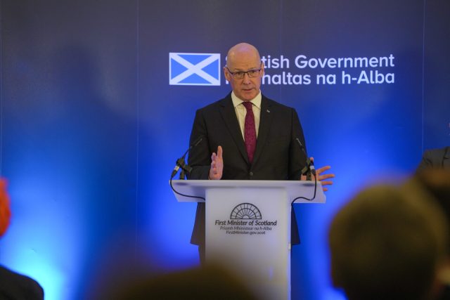 First Minister John Swinney speaking at a Scottish Government podium
