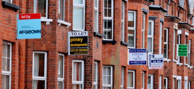 A terrace of brick houses covered in letting agents' To Let boards